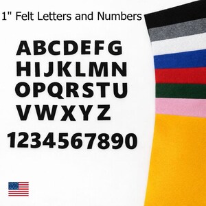 May include: Black felt letters and numbers, 2.5 cm in height, displayed on a white background. The alphabet and numbers 1-0 are shown. A colour palette of felt in various colours is visible on the right. The text "1" Felt Letters and Numbers" is at the top.