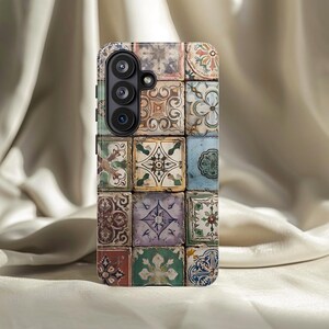 Op de afbeelding: Een smartphonehoesje met een mozaïektegelontwerp. De hoes heeft een patroon van kleine, vierkante tegels in verschillende kleuren, waaronder blauw, groen, bruin en paars. Elke tegel heeft een uniek bloemen- of geometrisch patroon.