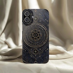May include: Black phone case with a detailed gold geometric design. The case features a central starburst pattern surrounded by circular motifs and intricate detailing. The case has a glossy finish and is designed for a smartphone.