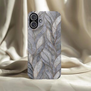 May include: A smartphone case with a leaf pattern design. The case features a repeating pattern of gray and white leaf shapes with gold-colored outlines. The phone case has a camera module with two lenses and a flash.