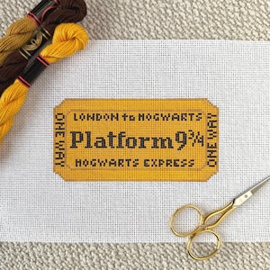 May include: A yellow and black "Platform 9 3/4" ticket design on white canvas, with the text "London to Hogwarts" and "Hogwarts Express". Gold embroidery floss and scissors are in the image.