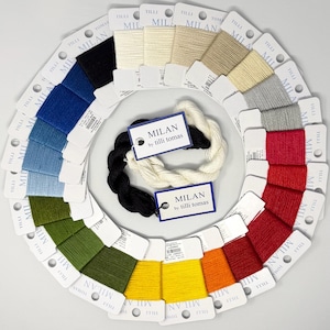 Può includere: Una collezione di campioni di filato Tilli Tomas Milan disposti in un motivo circolare su cartoncini bianchi, con uno spettro di colori tra cui nero, blu, verde, giallo, arancione, rosso, grigio e crema, con due matasse centrali e etichette.