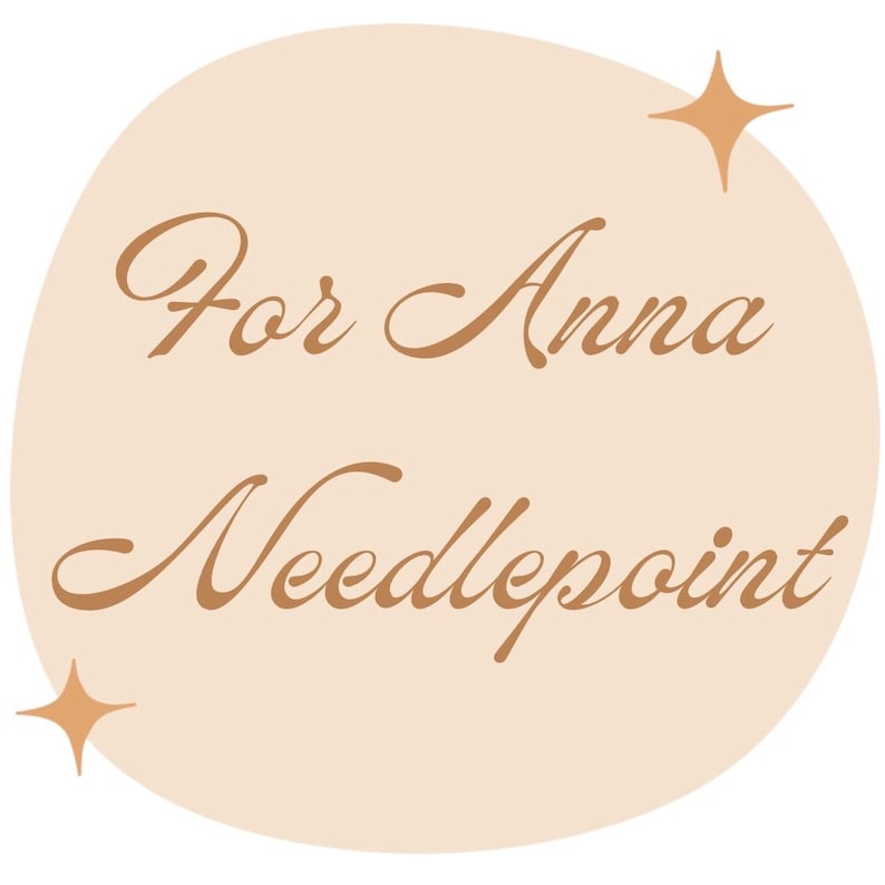 K&ouml;nnte beinhalten: Ein hellbeige kreisf&ouml;rmiges Design mit den Worten "For Anna Needlepoint" in einer braunen Schriftart. Zwei vierzackige Sterne befinden sich oben rechts und unten links im Kreis.