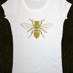 Op de afbeelding: Wit T-shirt met een gouden bij-print op de voorkant.