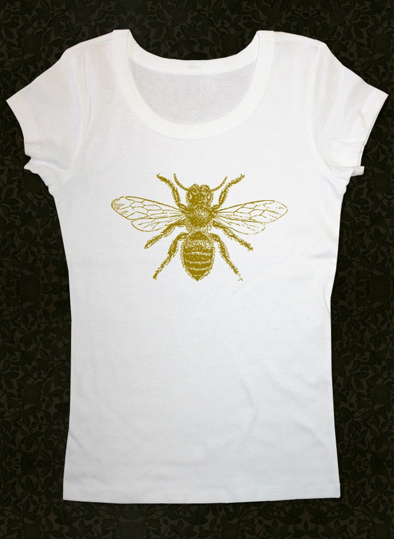 Op de afbeelding: Wit T-shirt met een gouden bij-print op de voorkant.