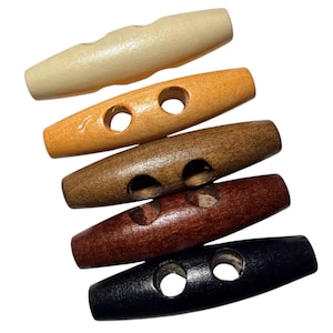 May include: A collection of six wooden toggle buttons in various shades of brown, from light beige to dark black. Each button has two holes and a rounded, elongated shape, suitable for coats or crafts.