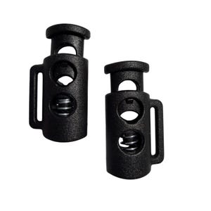 May include: Two black cord locks with a textured surface. Each lock has a cylindrical body with a spring inside, a handle, and two holes. These cord locks are used to tighten drawstrings or cords.