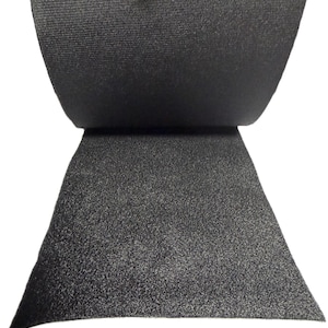 以下が含まれることがあります： 黒い面ファスナー素材の断面のクローズアップ。上部は折り返されており、ループ側のテクスチャ加工された表面が現れています。下部にはフック側が表示され、三角形の形をしています。