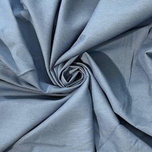 Peut inclure: Gros plan sur un tissu bleu clair à la texture subtile. Le tissu est disposé en plis souples, avec une spirale centrale créant un point focal. La couleur est une teinte sourde et froide, adaptée à divers projets textiles.