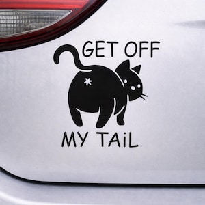 May include: A black cat decal with the text "GET OFF MY TAIL" on a car. The cat is depicted from the rear, with a star on its rear end. The decal is designed to be applied to a vehicle's exterior.