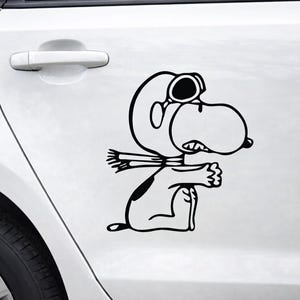 May include: Black and white vinyl decal of a cartoon character wearing goggles and a scarf, with arms outstretched. The decal is applied to a white car door, showcasing the character's outline and details.