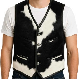 May include: A black and white cowhide vest with a V-neck and three silver buttons. The vest has a black leather trim and two small pockets. The vest is worn over a white t-shirt.