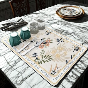 Puede incluir: Una mesa de comedor con un mantel individual floral, tazas de color turquesa, vasos transparentes, cubiertos y platos. El mantel individual tiene el texto "Aprovecha los detalles de la vida y cultiva el ambiente del hogar."