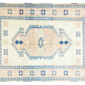 May include: A vintage rug with a cream background and a blue and pink geometric pattern. The rug has a border with a repeating star design.