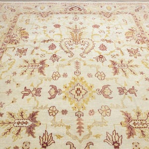 May include: A cream-colored rug with a traditional Persian design. The rug features intricate floral patterns in shades of red, brown, and gold.
