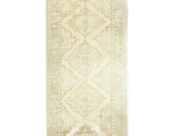 May include: A vintage cream-colored rug with a floral pattern. The rug has a subtle distressed look and a rectangular shape.