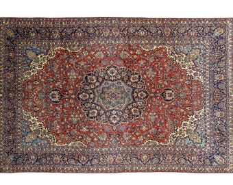 May include: A rectangular, ornate rug with a central medallion design. The rug features a red field with intricate floral patterns in blue, cream, and green. A dark blue border frames the design, creating a classic, elegant look. The rug is suitable for living rooms and bedrooms.