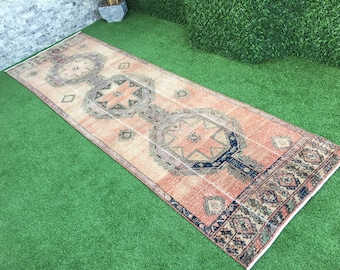 May include: A vintage runner rug with a traditional Persian design in shades of peach, cream, and navy blue. The rug has a distressed look and features intricate geometric patterns.