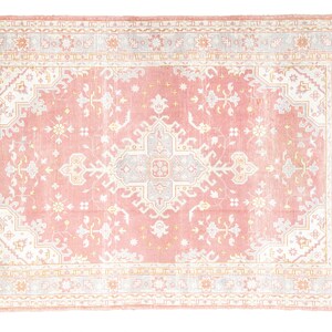 May include: A pink and white patterned rug with a floral design. The rug has a light pink background with a white border and intricate floral patterns in the center.