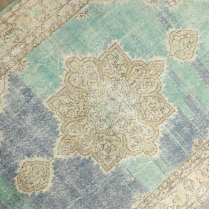 May include: A distressed, vintage-style rug with a central medallion design. The rug features a color palette of teal, beige, and muted blue. The border has an ornate pattern, and the rug has a faded, worn appearance.
