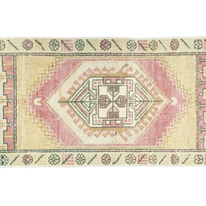 Op de afbeelding: Een vintage Turks tapijt met een roze en beige kleurschema. Het tapijt heeft een geometrisch patroon met een centraal medaillon. Het tapijt is in goede staat en heeft een versleten uitstraling.