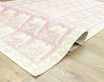 May include: A pink and cream patterned rug with a geometric design. The rug is folded in half and the edges are visible.