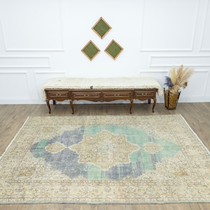 May include: A large, rectangular area rug with a central medallion design in shades of blue, beige, and teal. The rug has a distressed, vintage appearance with a detailed border. The rug is placed on a hardwood floor.