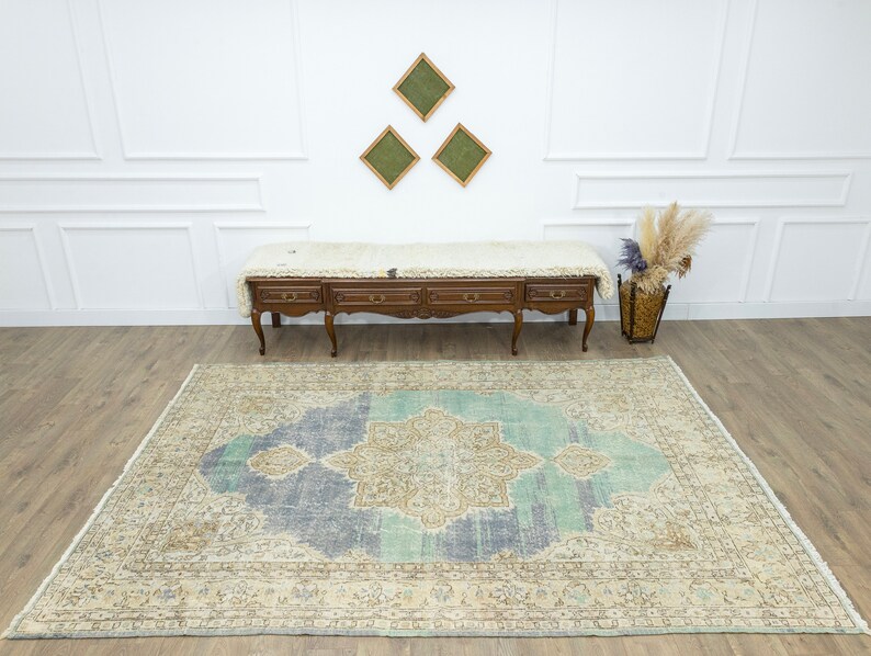 May include: A large, rectangular area rug with a central medallion design in shades of blue, beige, and teal. The rug has a distressed, vintage appearance with a detailed border. The rug is placed on a hardwood floor.