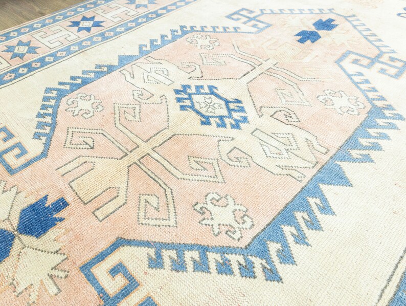 May include: A vintage rug with a light pink background and a geometric pattern in shades of blue and white.