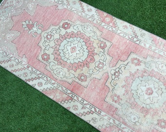 May include: A rectangular, vintage-style rug with a central medallion design. The rug features a faded color palette of pink, cream, and beige. The pattern includes floral and geometric elements, creating a traditional aesthetic.