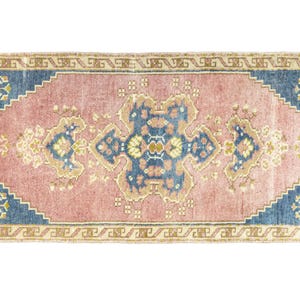 May include: A pink and blue vintage rug with a floral pattern. The rug has a fringed border and a central medallion design.