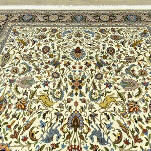 May include: Ivory-colored area rug with an intricate floral pattern in shades of blue, gold, red, and green. The rug features a detailed border with floral and geometric designs. The rug has a fringe on the edge.