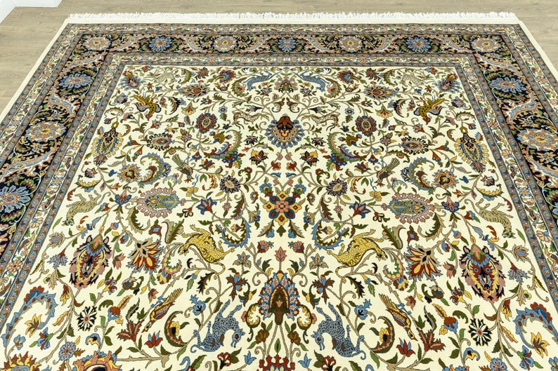 May include: Ivory-colored area rug with an intricate floral pattern in shades of blue, gold, red, and green. The rug features a detailed border with floral and geometric designs. The rug has a fringe on the edge.
