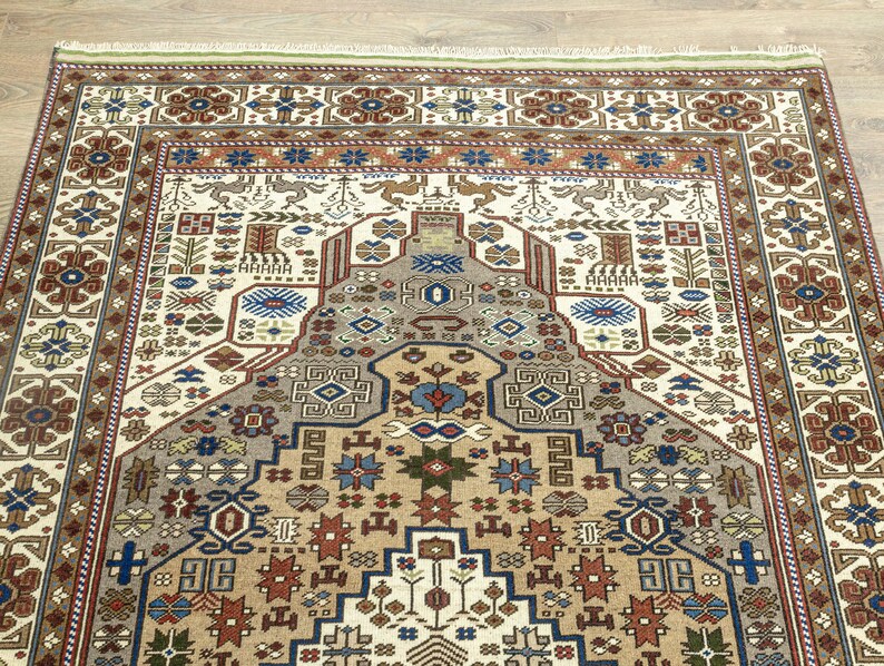 May include: A traditional rug with a cream background and intricate geometric patterns in shades of brown, red, blue, and green. The rug features a central medallion with a repeating pattern of stylized flowers and leaves.
