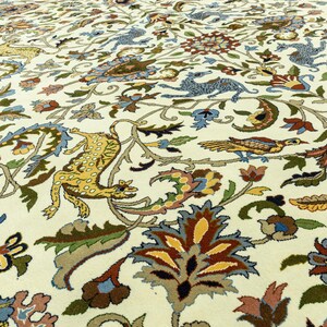 May include: Cream-colored rug with an intricate floral and animal pattern. The design features stylized birds, leopards, and floral elements in shades of blue, yellow, brown, and green. The rug's detailed design adds a touch of elegance.