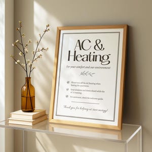以下が含まれることがあります： 「AC & Heating」の文字と省エネのための指示が書かれた額縁入りのサイン。サインはガラス棚の上にあり、花の入った花瓶の隣にあります。サインのメッセージは快適さと環境のためです。