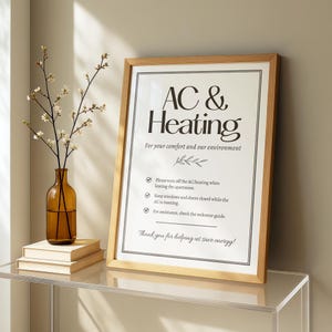 May include: A framed sign with the text "AC & Heating" in a modern font. The sign includes instructions for energy conservation and is displayed with a vase of flowers and books on a glass shelf.