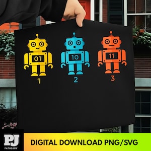 Puede incluir: Bolso tote negro con tres ilustraciones de robots coloridos. Los robots son amarillos, azules y naranjas, cada uno con un número único. Los números "01", "10" y "11" se muestran en los robots. Los números "1", "2" y "3" están debajo. También incluye el texto "DIGITAL DOWNLOAD PNG/SVG".