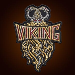 May include: An embroidered patch featuring a Viking warrior with a horned helmet and a long, flowing beard. The word VIKING is stitched in bold, gold-outlined letters across the centre. The design includes two intertwined dragon heads at the top.
