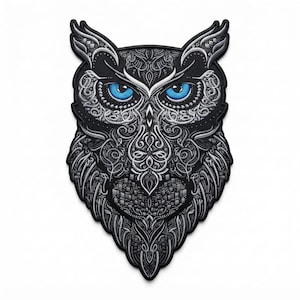 May include: An embroidered patch shaped like an owl head, featuring intricate black and white filigree patterns throughout the feathers. The owl has two prominent, bright blue eyes that stand out against the monochromatic, detailed embroidery.