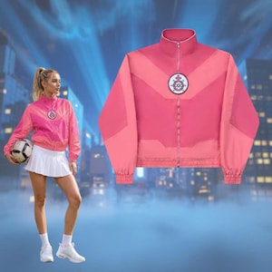 Könnte beinhalten: Eine rosa-korallfarbene Jacke mit Reißverschluss, hohem Kragen und rundem Emblem auf der Brust. Die Jacke hat ein Colorblock-Design und gerippte Bündchen. Die Jacke wird mit einem weißen Tennisrock und Turnschuhen gezeigt. Sportlicher Stil.