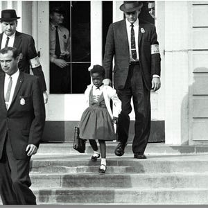 May include: A monochrome photograph showing a young girl in a dress and carrying a bag, escorted by men in suits and hats. The girl is walking down steps, accompanied by the men. The image captures a historical moment.