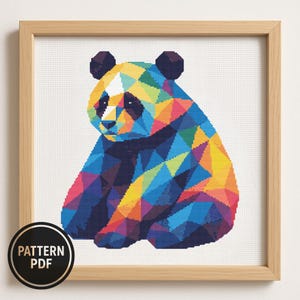 May include: A framed cross-stitch pattern featuring a geometric panda bear design. The panda is composed of colorful triangular shapes in shades of blue, yellow, orange, and purple. The text "PATTERN PDF" is in a black circle in the lower left corner.