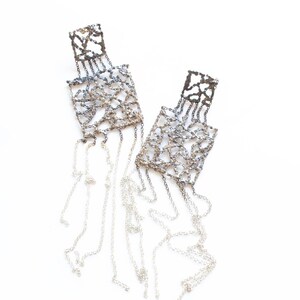 May include: A pair of silver earrings with a delicate chain design and a fringe of dangling chains.