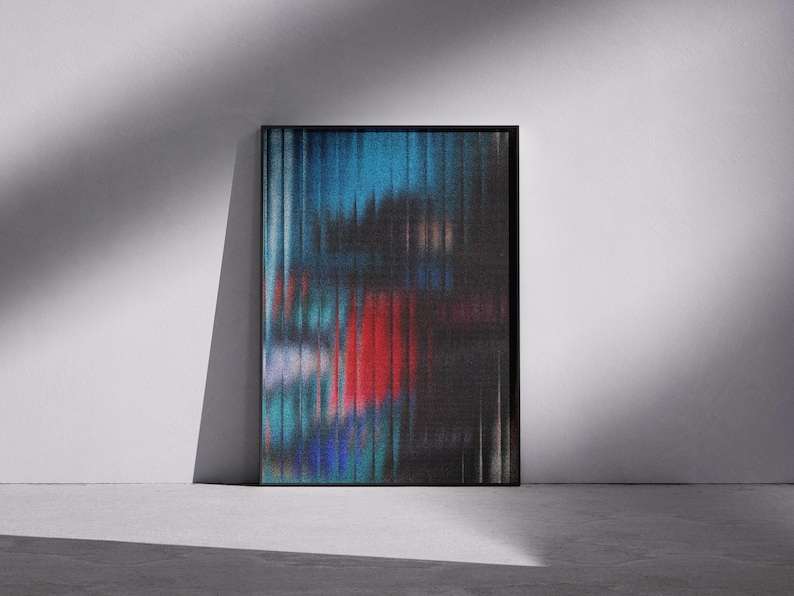 Könnte beinhalten: Abstrakter Kunstdruck in einem schwarzen Rahmen. Das Kunstwerk zeigt ein verschwommenes, vertikales Design mit Blau-, Rot- und Schwarztönen. Die gerahmte Kunst lehnt an einer weißen Wand, mit Schatten auf einem Betonboden.