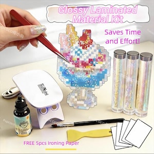 Op de afbeelding: Een glanzende, gelamineerde materiaalset met de tekst "Bespaart tijd en moeite!" bevat een witte UV-lamp, een fles vloeistof, een kwast, een gele spatel en strijkpapier. Ook inbegrepen zijn drie transparante buizen en een decoratief pixelontwerp.