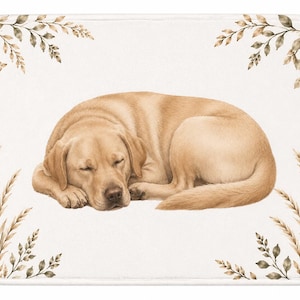 May include: A rectangular bath mat with a white background featuring a central illustration of a sleeping yellow Labrador retriever. The corners are decorated with botanical sprigs in shades of brown and muted green, framing the dog.