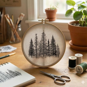 May include: A circular embroidery hoop with a black and white forest design. The image shows a wooden hoop holding a beige fabric with a stitched forest scene. The scene includes different types of trees. The hoop is on a wooden surface.