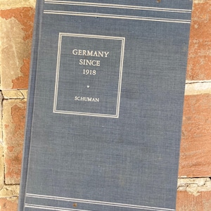 Puede incluir: Un libro de tapa dura azul con el título "Germany Since 1918" y el nombre del autor "Schuman" impreso en blanco en la portada.