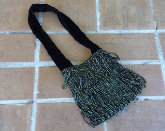May include: A small black velvet handbag with a beaded fringe in shades of green and blue.